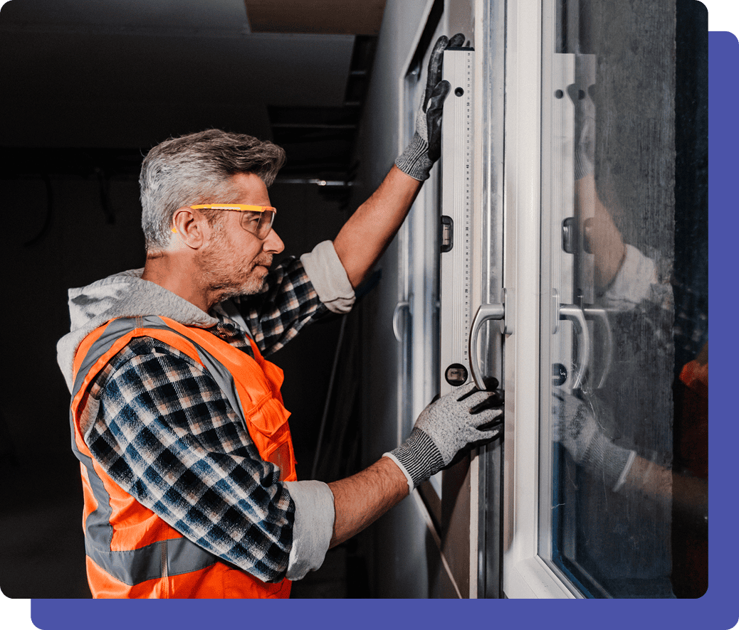 Worker installing a window with tools.
