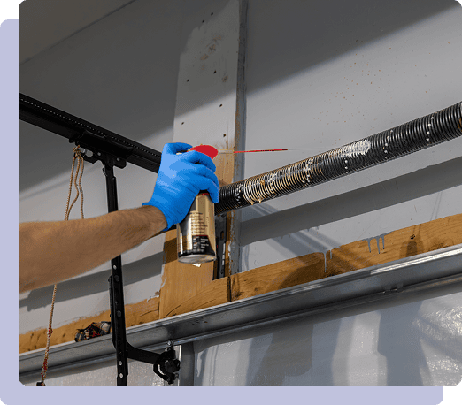 Lubricating garage door spring with spray can.